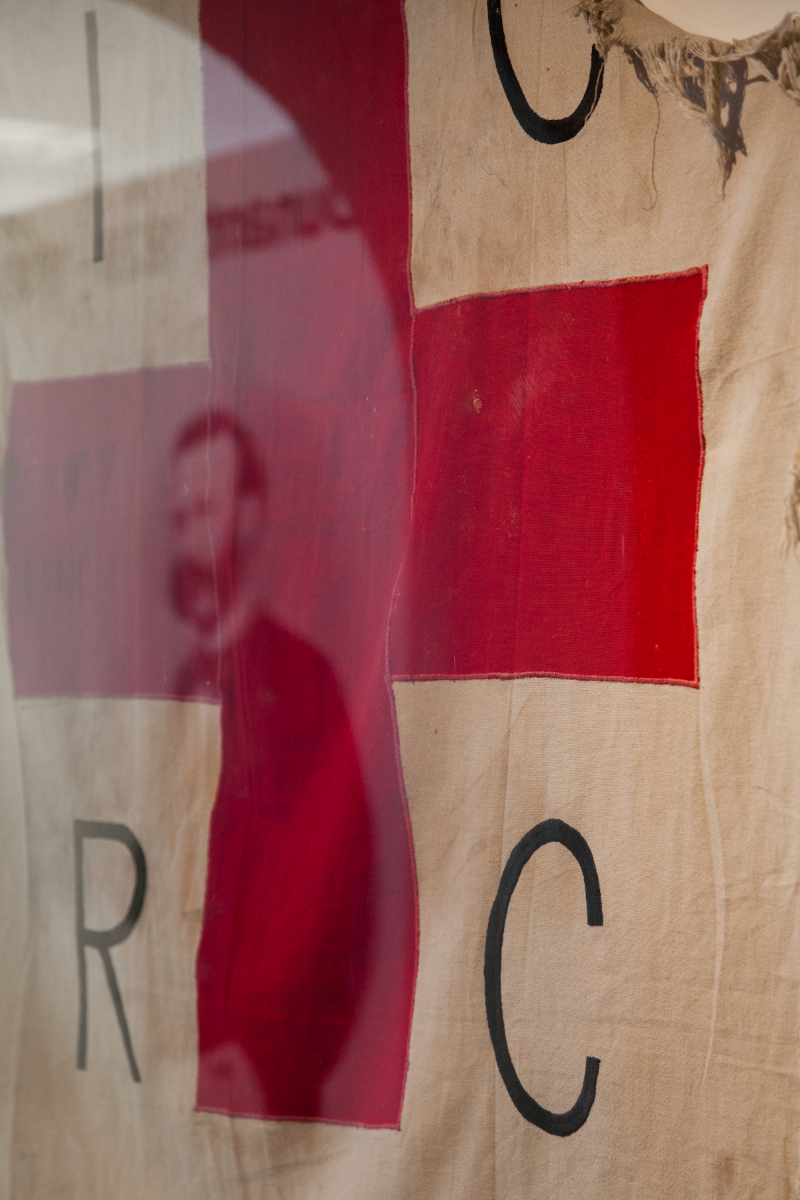 Fahne des IKRK mit durchschimmerndem Porträt von Henry Dunant.